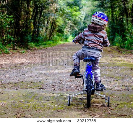 child riding a bicycle in the woods. Horizontal
