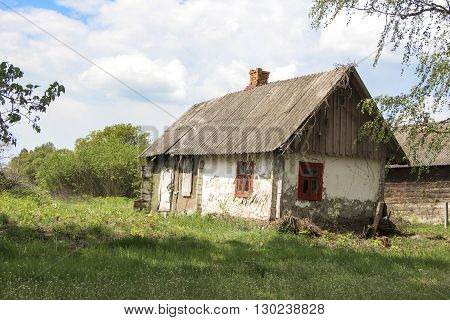 Old abandoned farmhouse near blooming trees against the bright spring sky - life goes on.
 