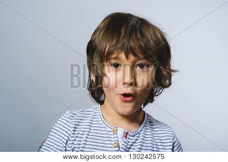 Portrait of happy boy going surprise on gray background.