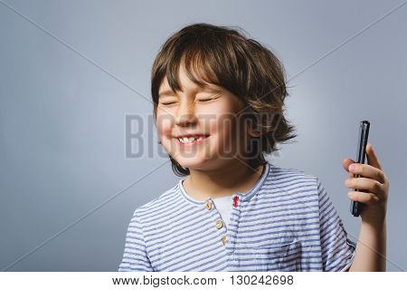 Portrait of happy boy with mobile going surprise on gray background.
