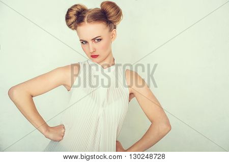 Close-up portrait of offended beautiful girl with funny hairstyle looking at camera.