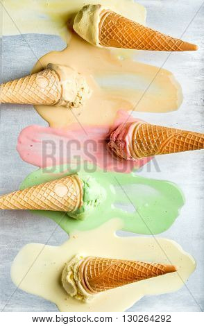 Colorful ice cream cones of different flavors. Melting scoops. Top view, steel metal background, vertical