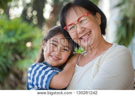Happy little Asian girl hugging her grandmother