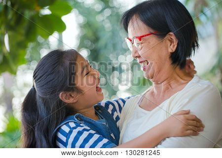 Happy little Asian girl hugging her grandmother