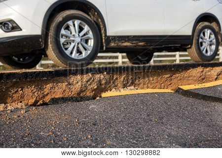 A car on crack of asphalt road after earthquake