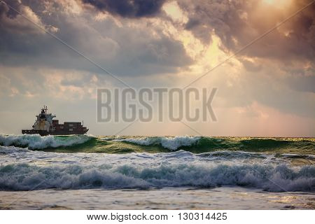 Sun setting at the sea with sailing cargo ship scenic view