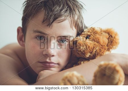 Teenage Boy Snuggling With Brown Teddy Bear