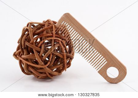 horizontal front view of a wooden comb next to a ball of twisted brown wood branches isolated on white background
