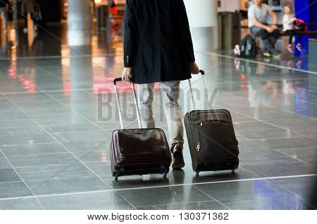 A man with two hand baggage suitcases on a airport