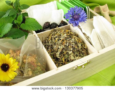 Tea box with loose tea, tea bags and fresh tea herbs