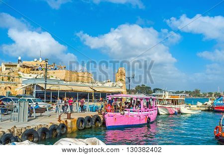 ACRE ISRAEL - FEBRUARY 20 2016: The pink pleasure boat waits the tourists to make a trip along the beautiful coast of old Akko on February 20 in Acre.