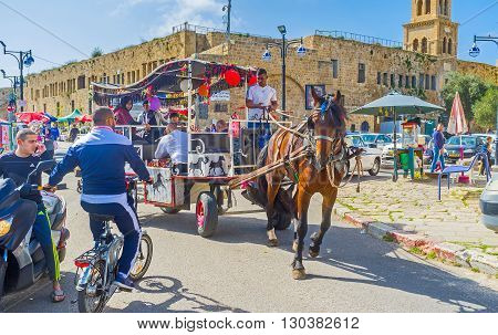ACRE ISRAEL - FEBRUARY 20 2016: The tourist carriage tries to ride inthe narrow port promenade of old Akko on February 20 in Acre.