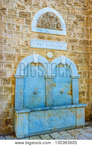 TEL AVIV ISRAEL - FEBRUARY 25 2016: The old marble fountain with the hebrew inscriptions and patterned relief is built in the old house wall on February 25 in Tel Aviv.