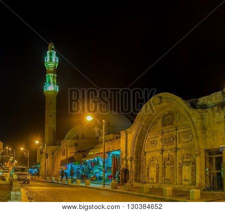 TEL AVIV ISRAEL - FEBBRUARY 25 2016: The evening view of Mahmoudiya Mosque with the bright illuminated minaret and its stone sabil on February 25 in Tel Aviv.