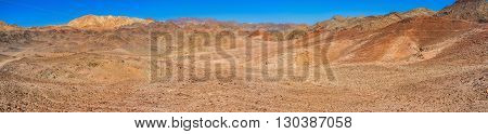 The red valley in Eilat mountains egion with the bright yellow peak on the background Israel.