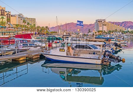 EILAT ISRAEL - FEBRUARY 23 2016: The motor boats and yachts in Lagoona with the scenic rocky mountains of Jordan in the sunset lights on February 23 in Eilat.