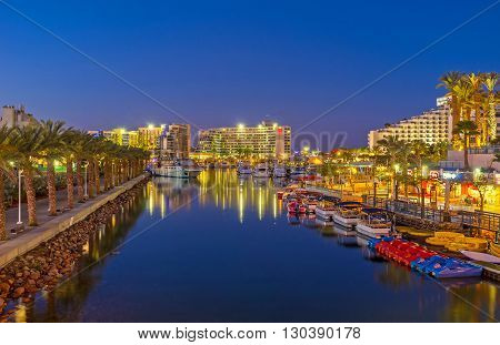 EILAT ISRAEL - FEBRUARY 24 2016: The romantic evening promenade along marina with moored boats and yachts on February 24 in Eilat.
