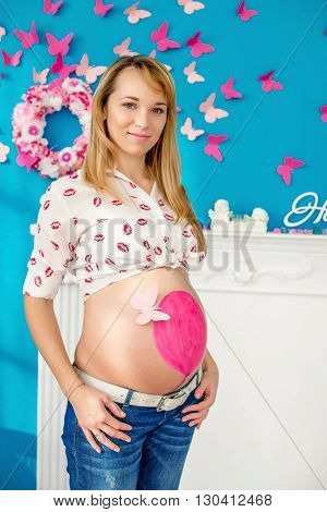 Happy pregnant woman pink ball painted on the belly and pink butterfly attached to the ball