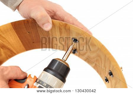 Making wooden drum with electric crewdriver isolated closeup