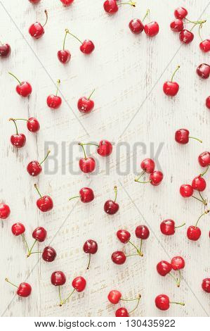 Cherry background. Red cherries scattered on rustic table. Overhead view, blank space