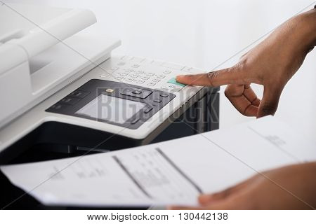 Close-up Of Young Businesswoman Hand Operating Printer In Office