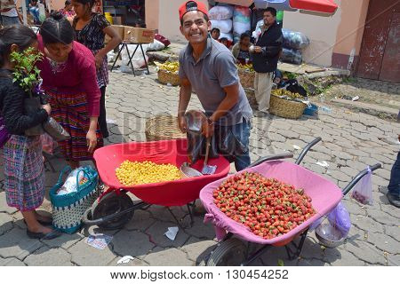 QUETZALTENANGO GUATEMALA APRIL 28 2016 : Youg man sells fruits in Quetzaltenango maket. This native market is the most colorful in Central America