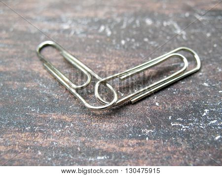 two paperclips join together on old table close up two paperclip link
