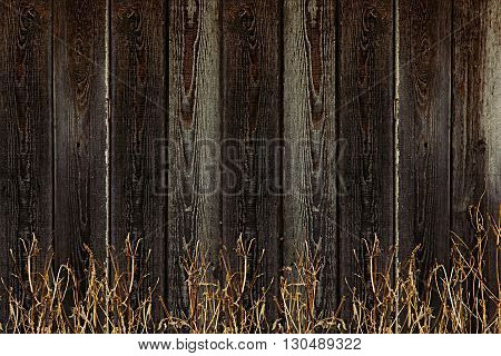 Old wooden fence. Vintage boards and dry grass. Wooden background. Wooden texture.