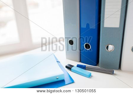 business, document, paperwork, office supply and education concept - close up of ring binders and files with highlighter pen or marker on table