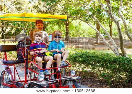Yound dad and two little kid boys biking on bicycle in zoo. Family with active leisure and watching animals. Father and sons having fun together. Miami zoo, Florida.