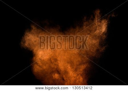 Orange powder explosion on black background. Colored powder cloud. Colorful dust explode. Paint Holi.