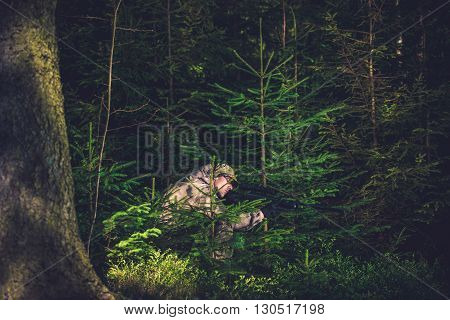 Hiding Poacher with Rifle in Deep Spruce Forest. Hunting Poacher. Poaching Theme.