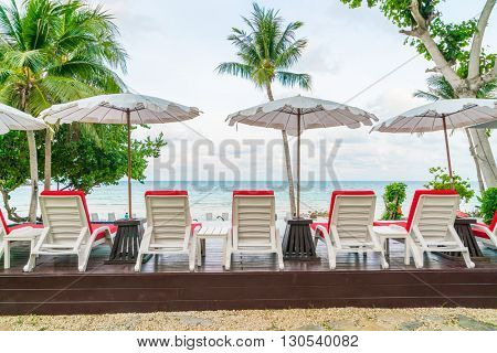 Beautiful beach chairs with umbrella around outdoor swimming pool neary sand and sea