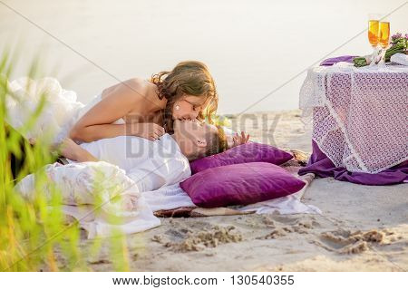 Romantic and happy young bride kissing on the lake.A man lies on his back and she leaned over him.