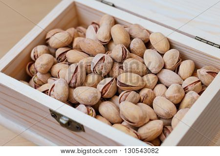 Pistachio nuts in a shell, salty, roasted in a wooden box