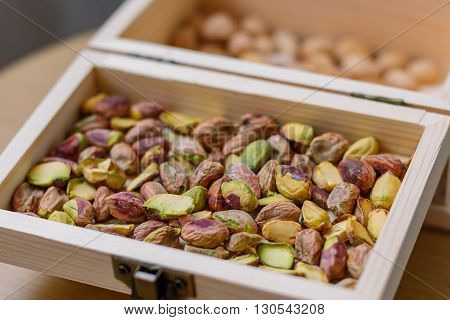 Green pistachio nuts without shell in a wooden box