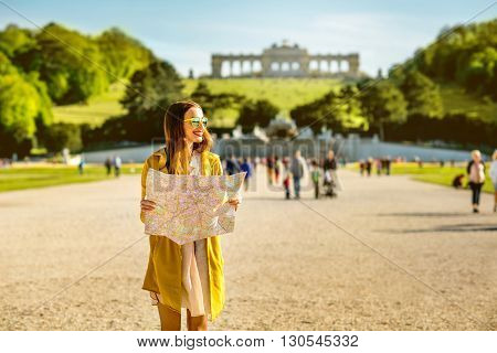 Young female tourist traveling with paper map in Schoenbrunn palace with Gloriette building on the background