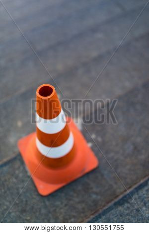 traffic cone, with white and orange stripes on gray staircace copy space.