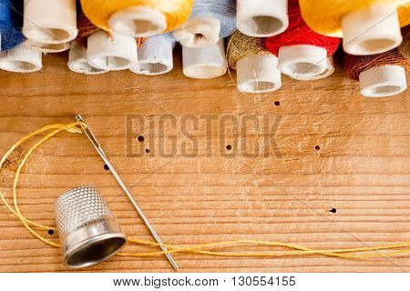 needle with thread and thimble o the wooden desk