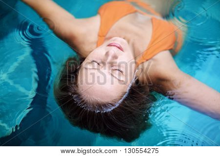 Beautiful female model with body long hairs underwater and wet face skin swimming with pleasure and relaxing in luxury spa pool. Healthy lifestyle woman beauty people health care water treatment