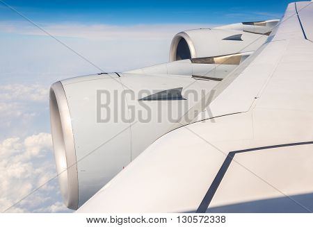 Wing with engines of Airbus A380 airliner flying over clouds