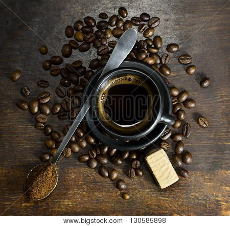 Cup of hot coffee with spoon and candy on wooden background