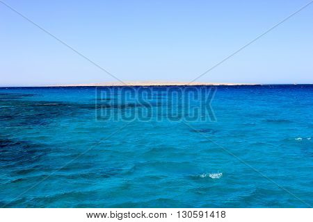 Sea Blue Water Background at Sun Light. Beach can be seen in the distance.