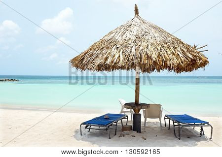 Grass umbrella at the beach on Aruba island at sunset