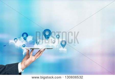 Businessman hand holding tablet with abstract map and location pins. Traveling concept