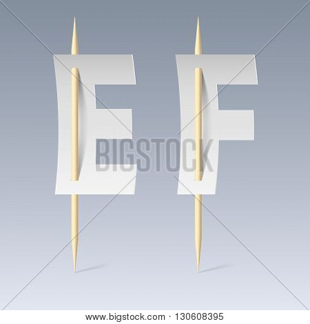 White paper cut font on toothpicks on grey background. E and F letters