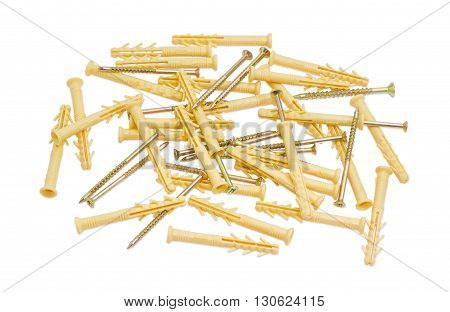 Pile of yellow plastic wall plugs and zinc plated chipboard screws with countersunk heads on a light background