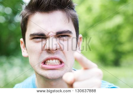 Outdoor Head And Shoulders Portrait Of Angry Young Man
