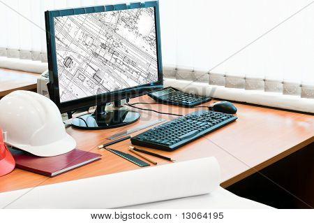 Luogo di lavoro con Computer, cappello duro e disegni di progetto. Disegno nello schermo