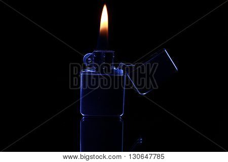 black gasoline lighter with flame on dark background